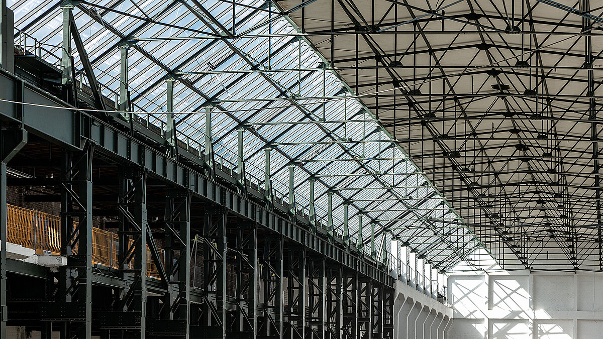 Innenansicht des Factory Campus Düsseldorf mit Glasdach, Stahlträgerkonstruktion und industriellem Charme.