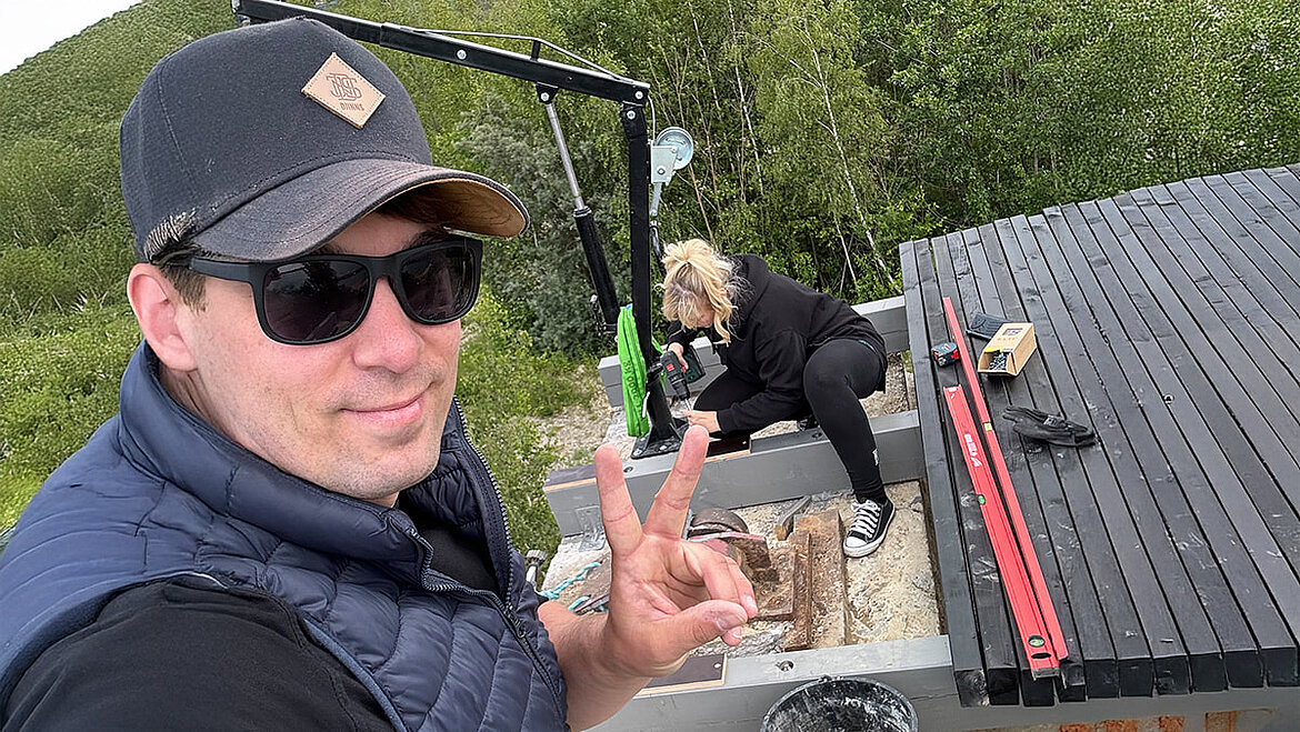 Mann beim Arbeiten an schwarzer Metallkonstruktion im Grünen.