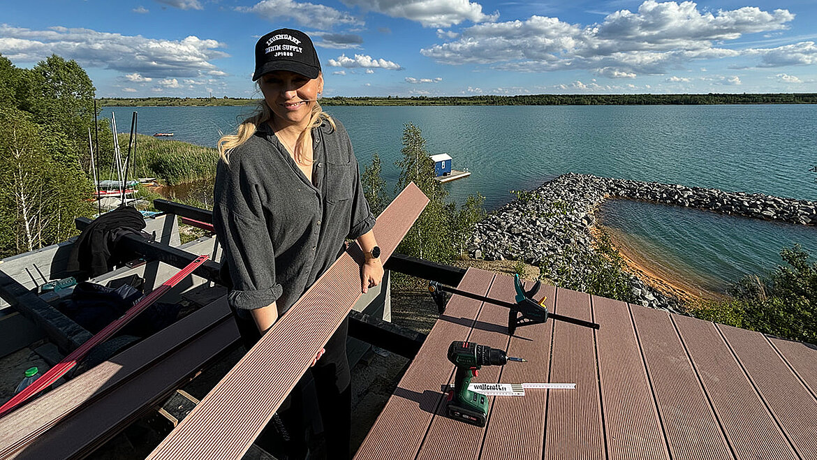 Person montiert dekorative Holzpaneele auf einem Dach mit Seeblick.